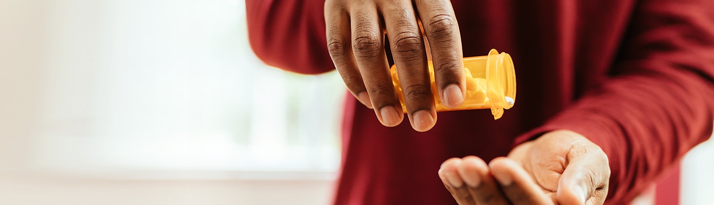 A hand shaking out pills from a bottle.