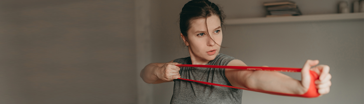 A woman uses a resistance band to represent resiliency.