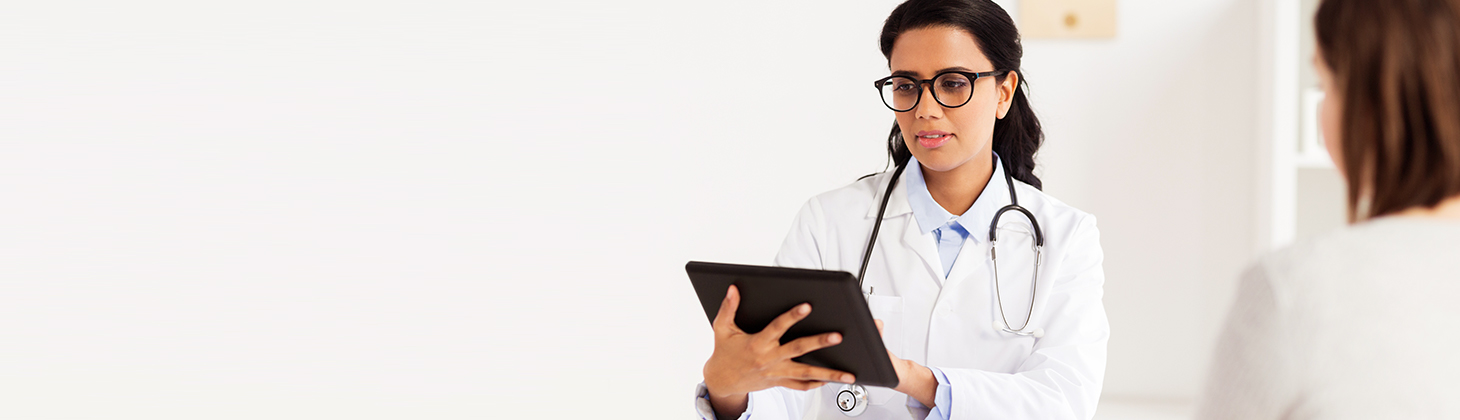 Female doctor with stethoscope looking at a tablet device.