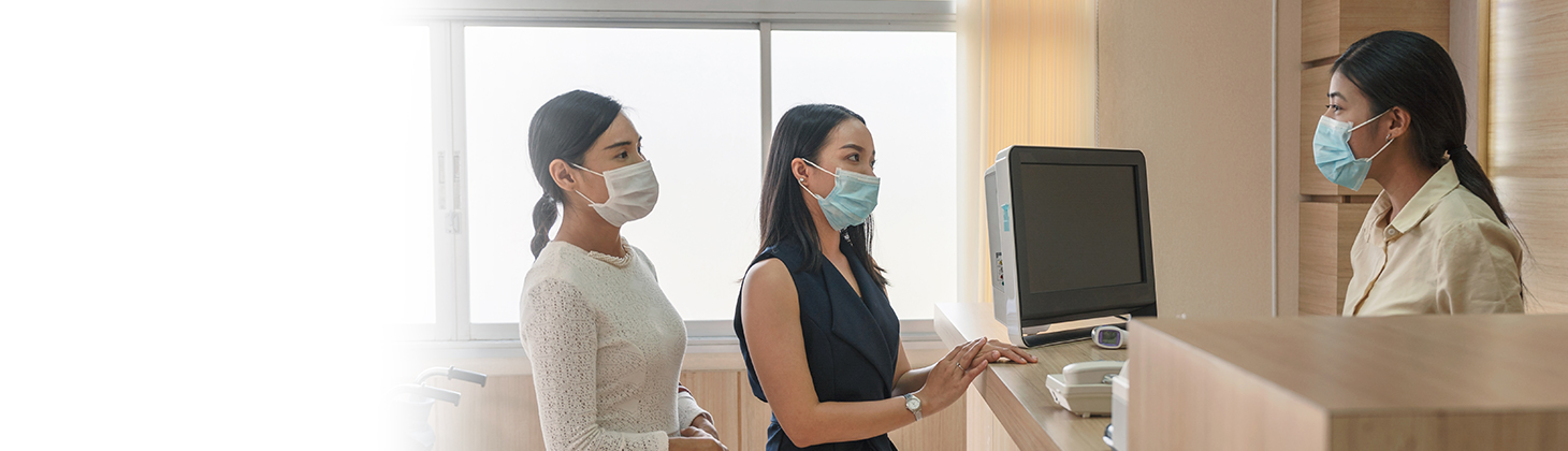 People in face masks at a desk in a health care setting.