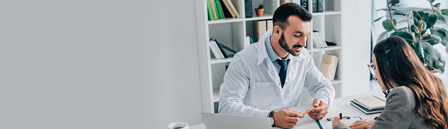 A doctor looks at a form that his patient is writing on.