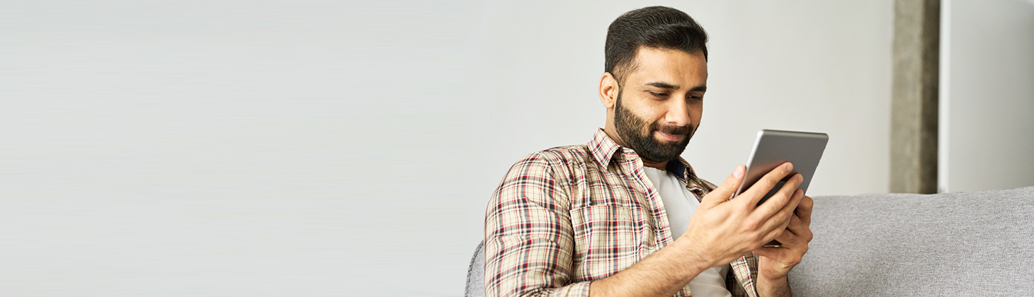 Man looks at a tablet while sitting on his couch