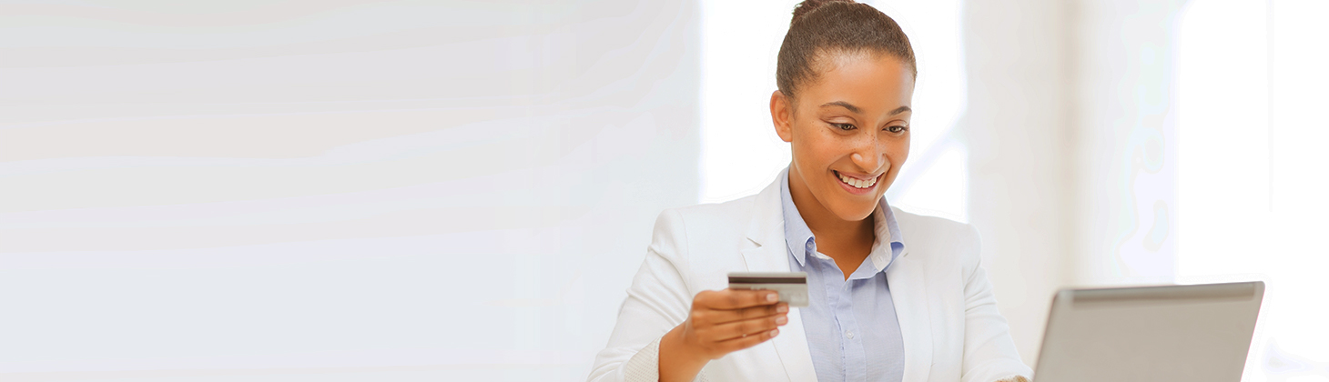 A woman at her computer holding a credit card