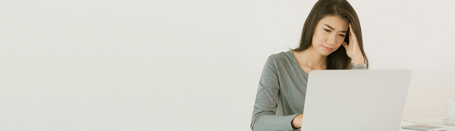 A woman works at her computer and looks distressed.