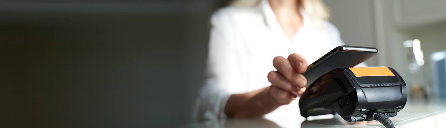 A customer holds her smartphone over a credit card payment processor.