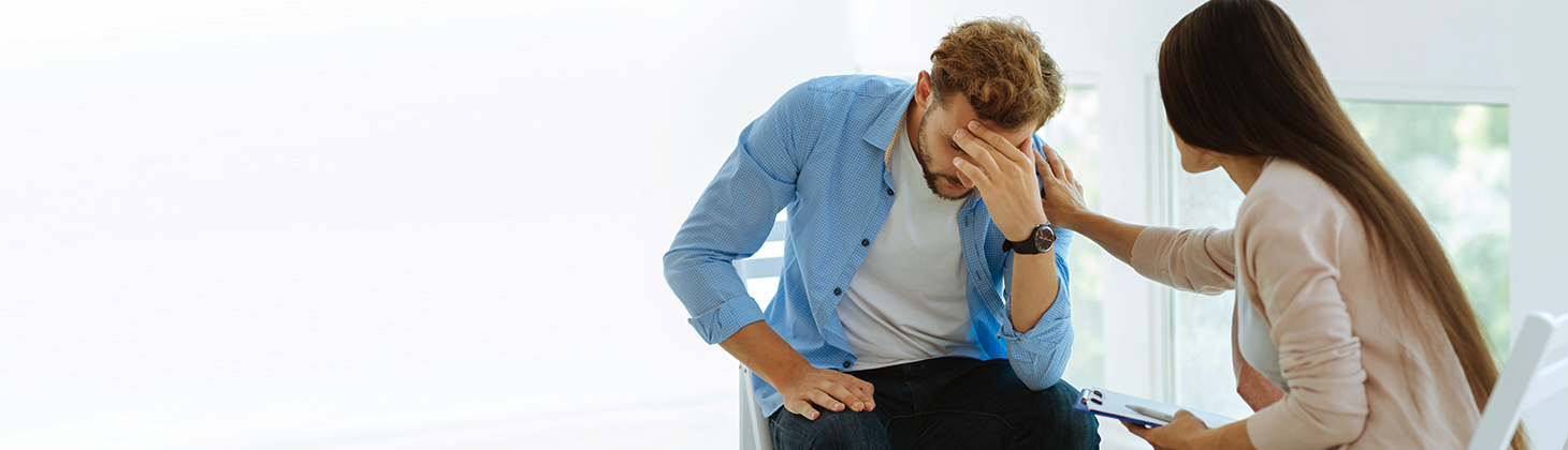 A therapist comforts a man wearing professional attire.