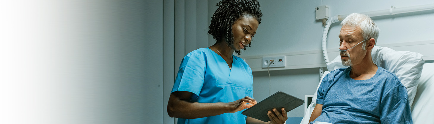 Doctor stands near a patient and looks at paperwork.